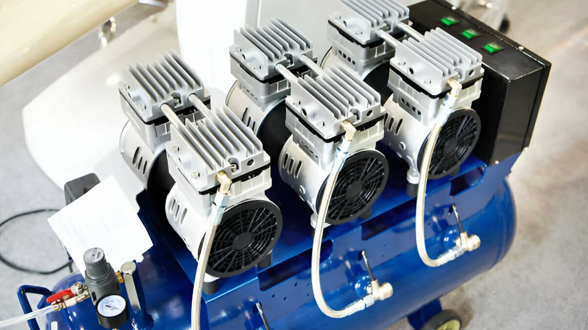 Modern dental air compressor with multiple motor heads and pressure gauge, positioned on a clinic floor.